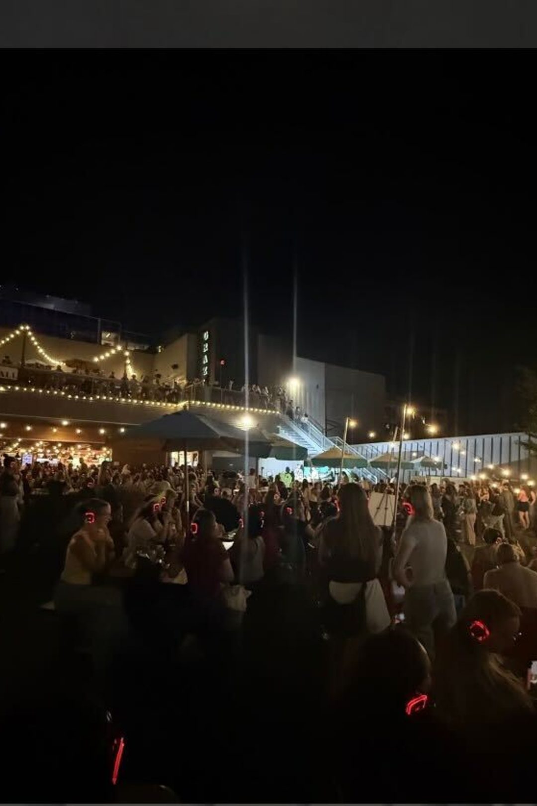 Image of audience outdoors with headphones on at night watching live dating